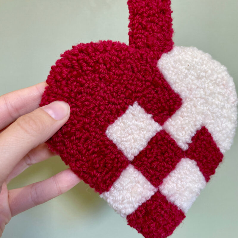 Håndlavet tuftet julehjerte i røde og hvide nuancer, perfekt til julepynt eller som gave.