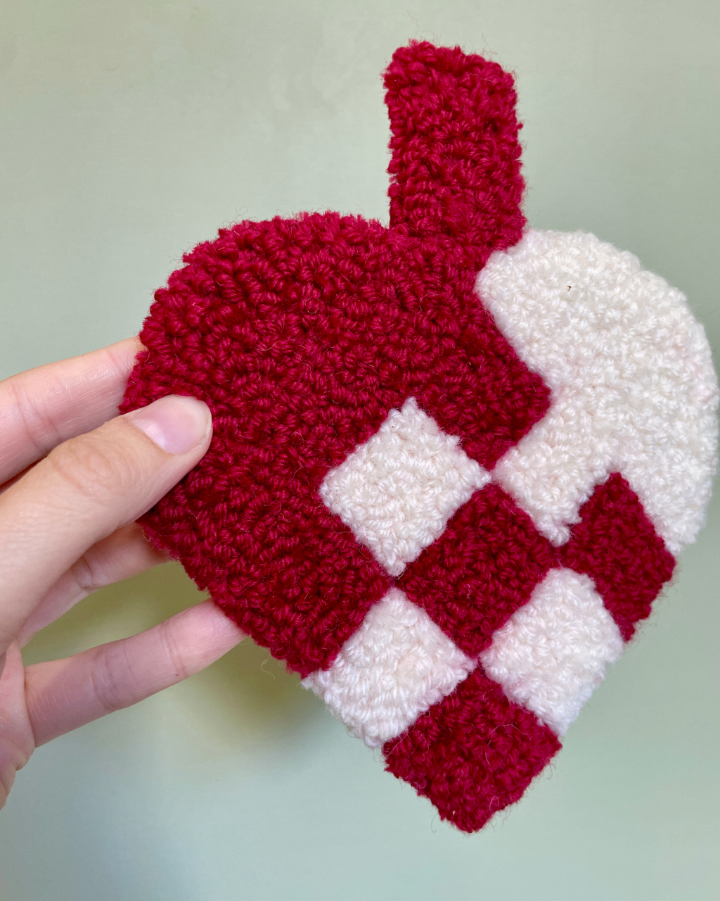 Håndlavet tuftet julehjerte i røde og hvide nuancer, perfekt til julepynt eller som gave.