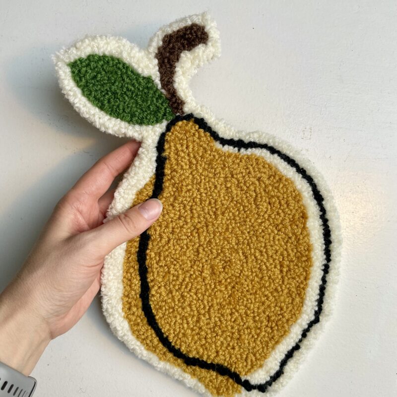 Håndlavet tuftet citron i varme gule nuancer med sort kontur og grønt blad på lys baggrund